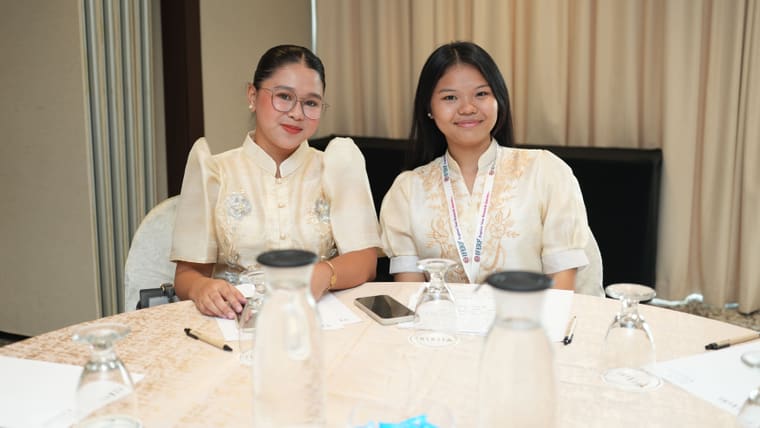 Two delegates seated at a table during a conference networking break