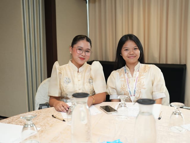 Two delegates seated at a table during a conference networking break