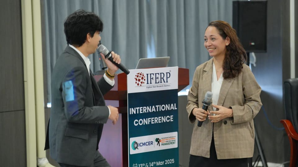 A session chair and presenter answering questions at the podium
